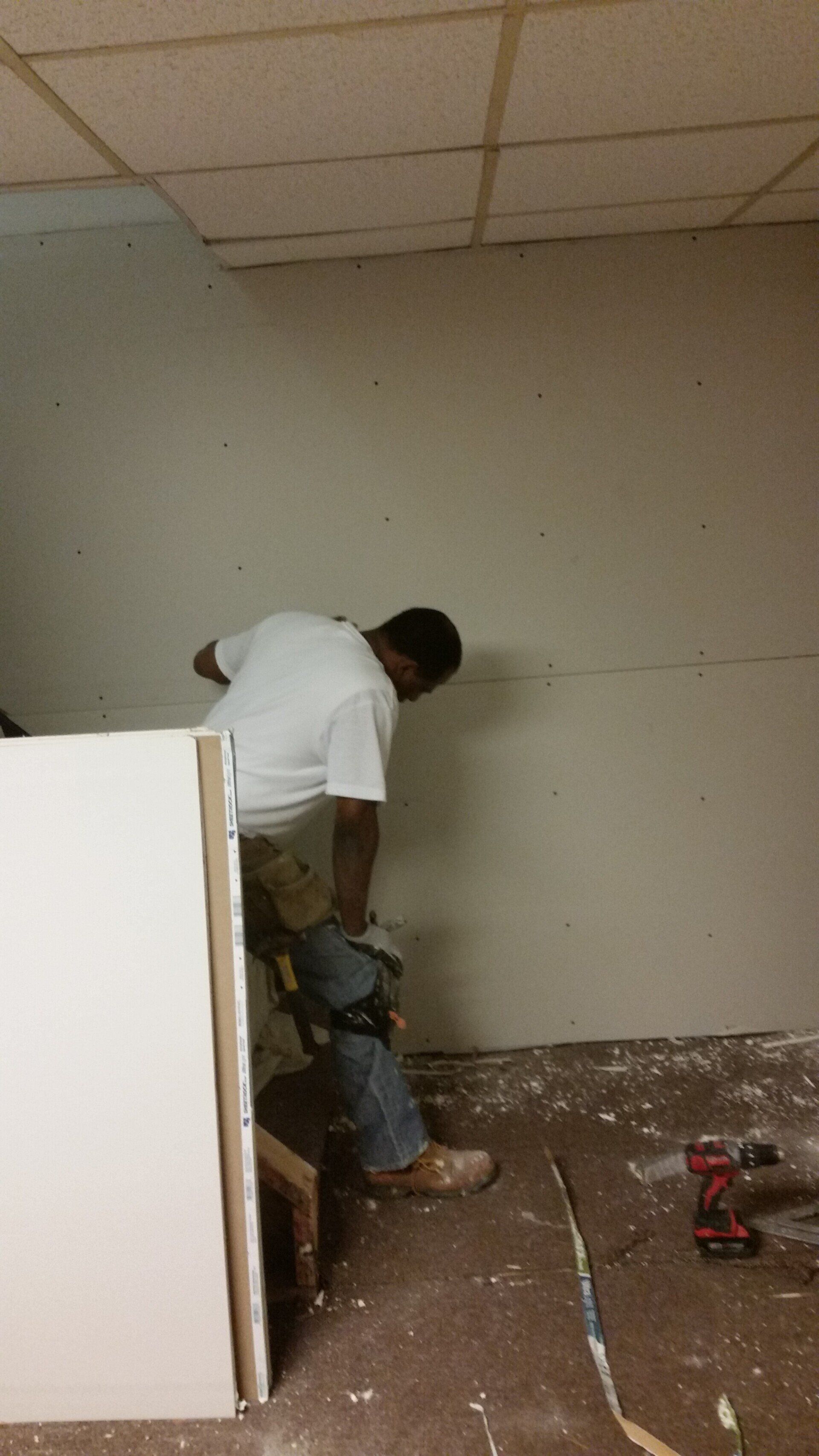 A man is working on a wall in a room.