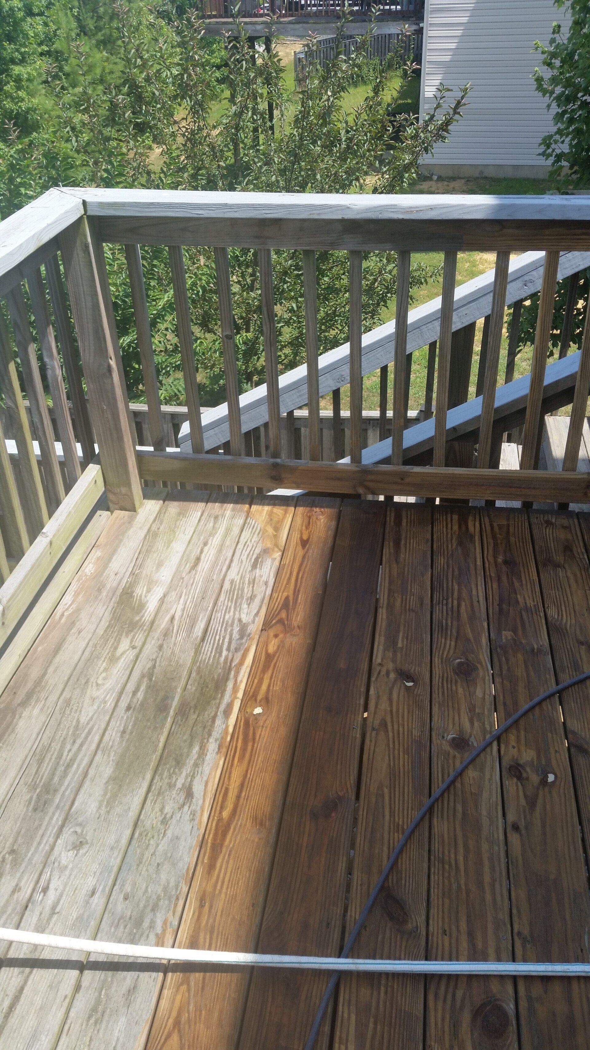 A wooden deck is being cleaned with a pressure washer.