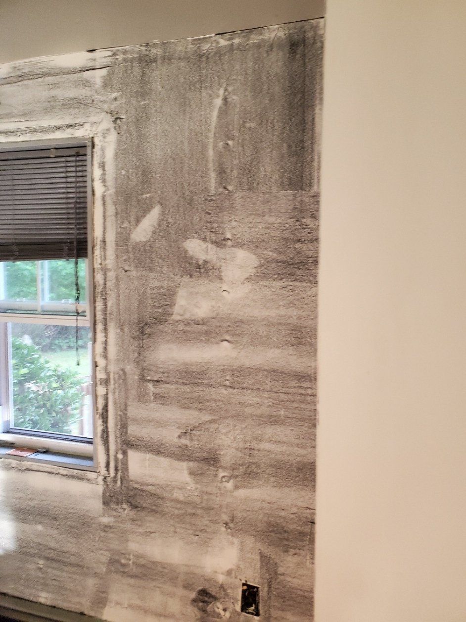 A room with a window and a wall that is being painted.