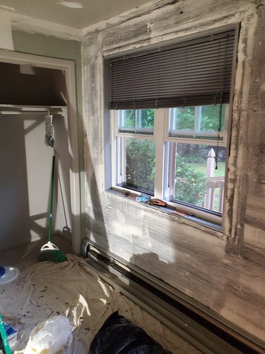 A room with a window and a broom in it.