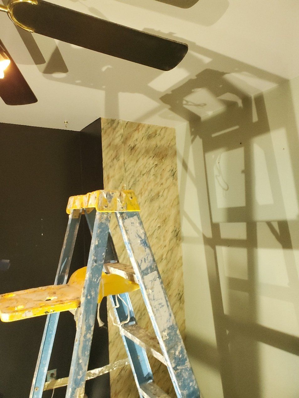 A ladder in a room with a ceiling fan