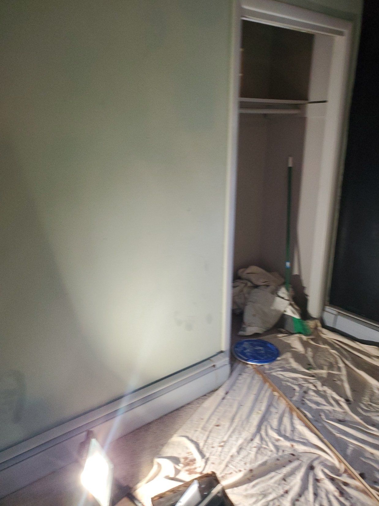 A closet is being painted in a room with a light on the floor.