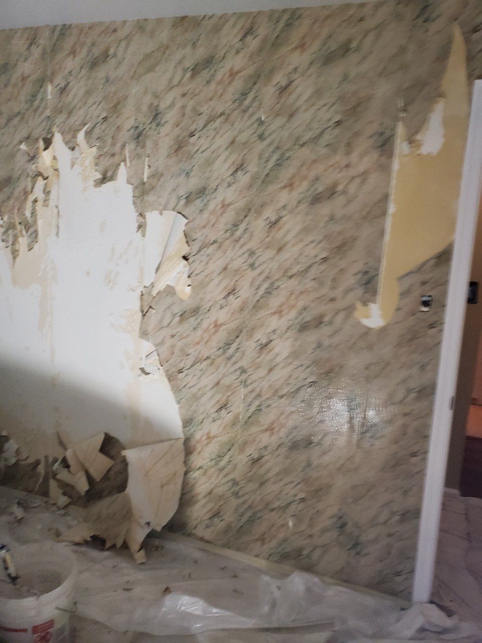 A wall with a lot of wallpaper peeling off of it.