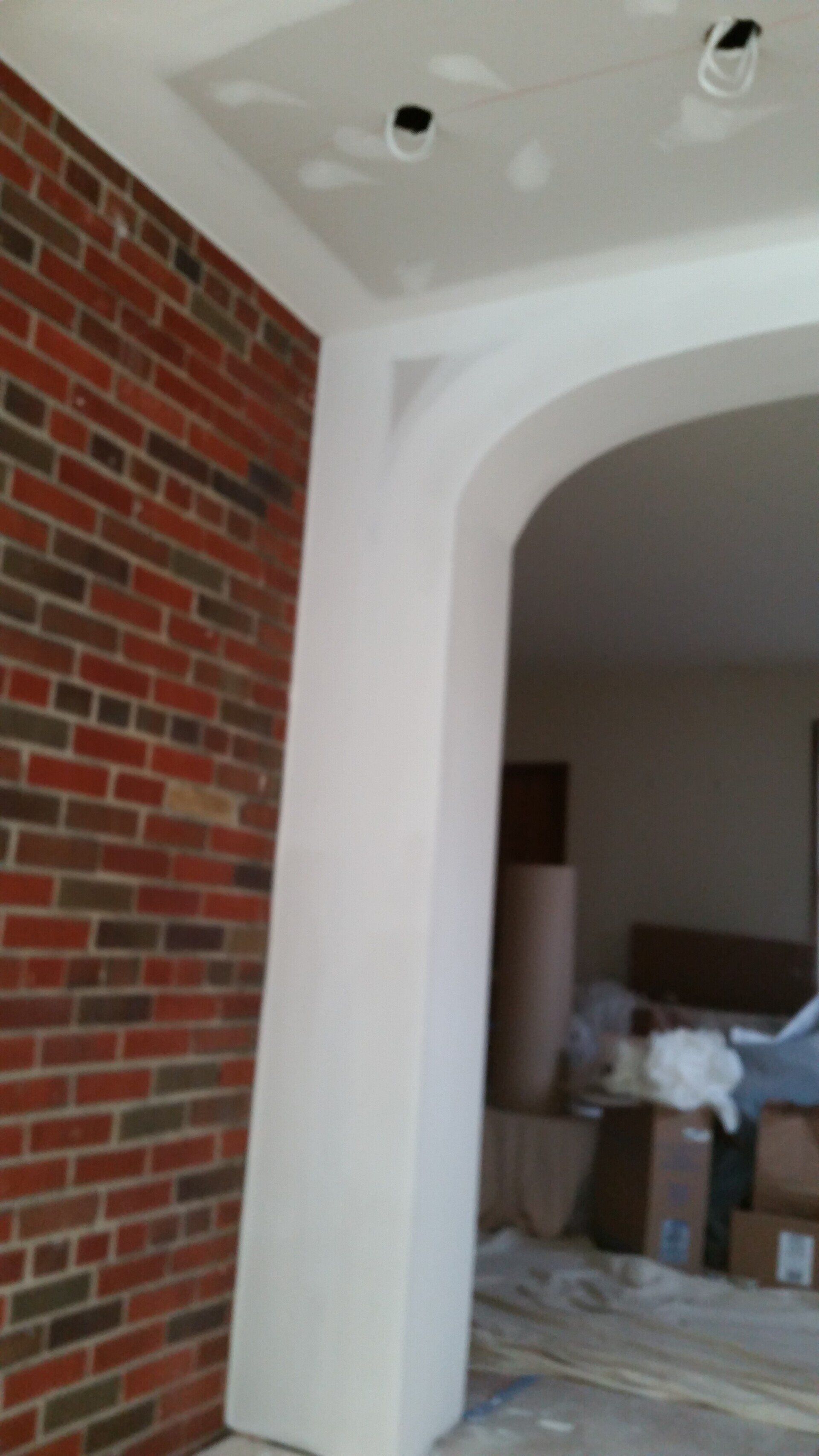 A room with a brick wall and a white archway