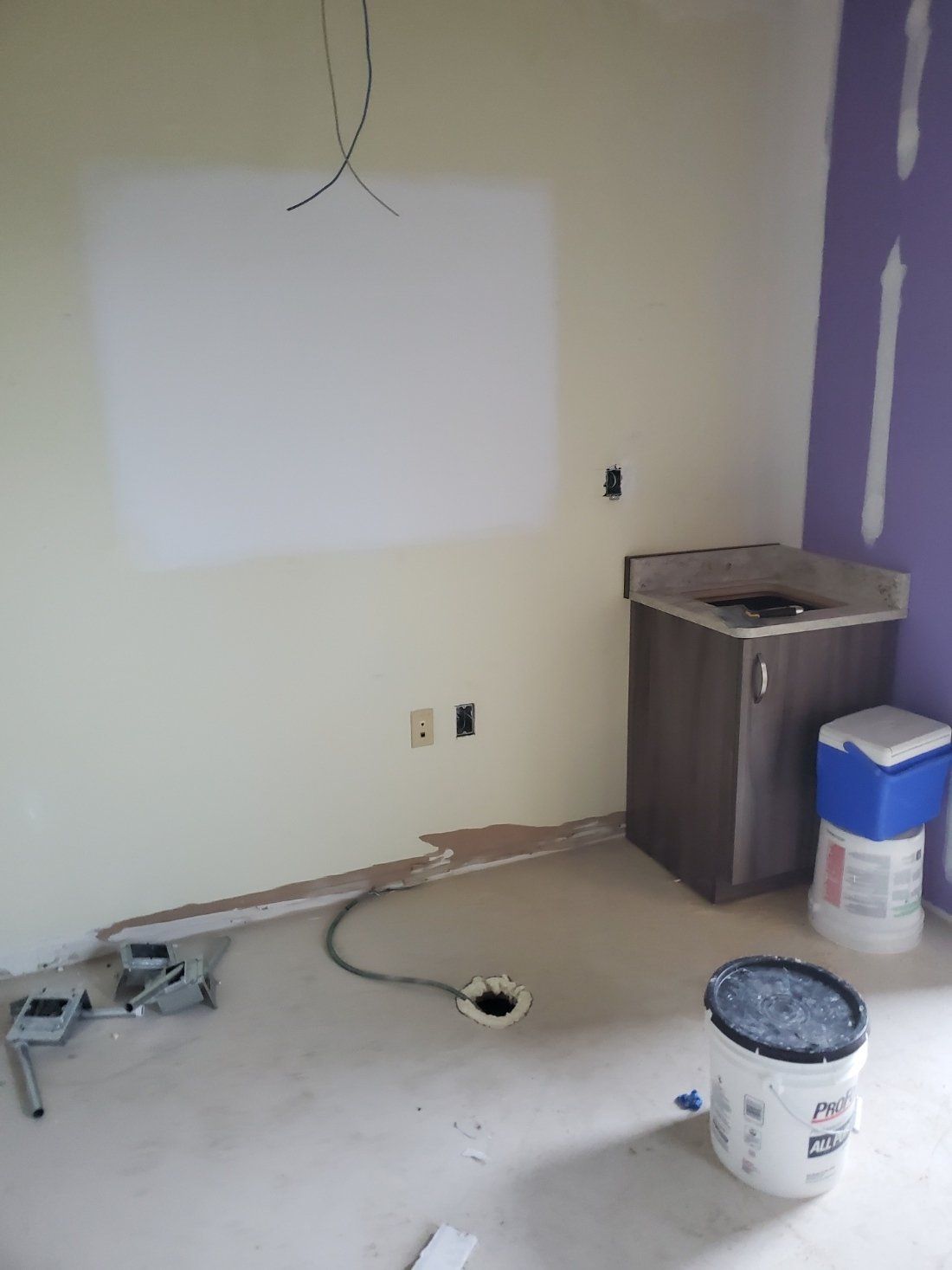 A room with a sink and a bucket of paint on the floor