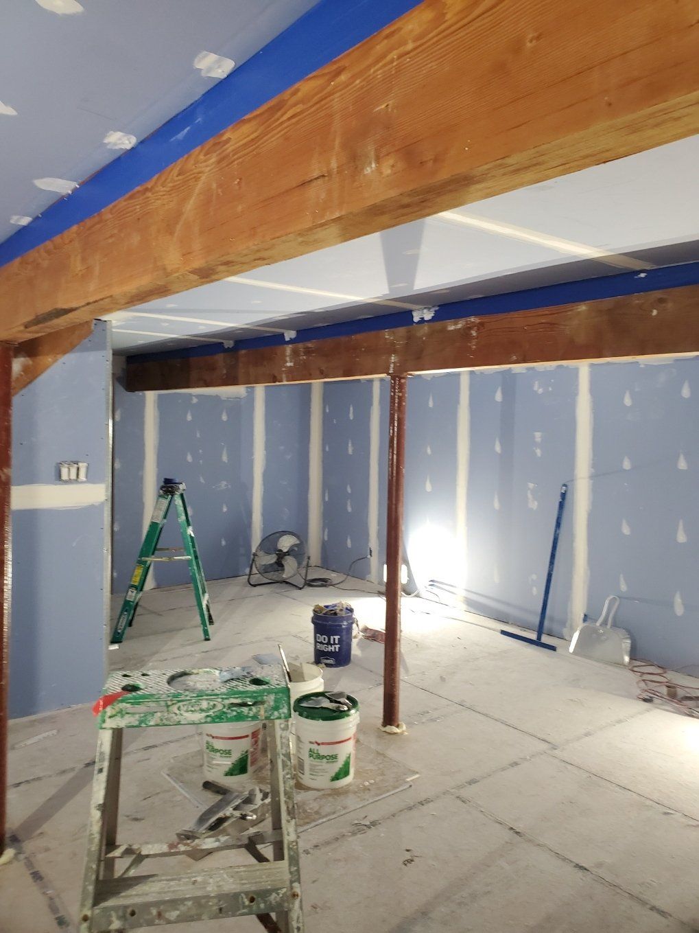 A room with buckets of paint and a ladder in it