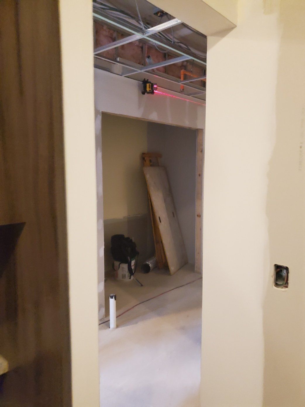 A room with a ceiling that is being built and a door that is open.