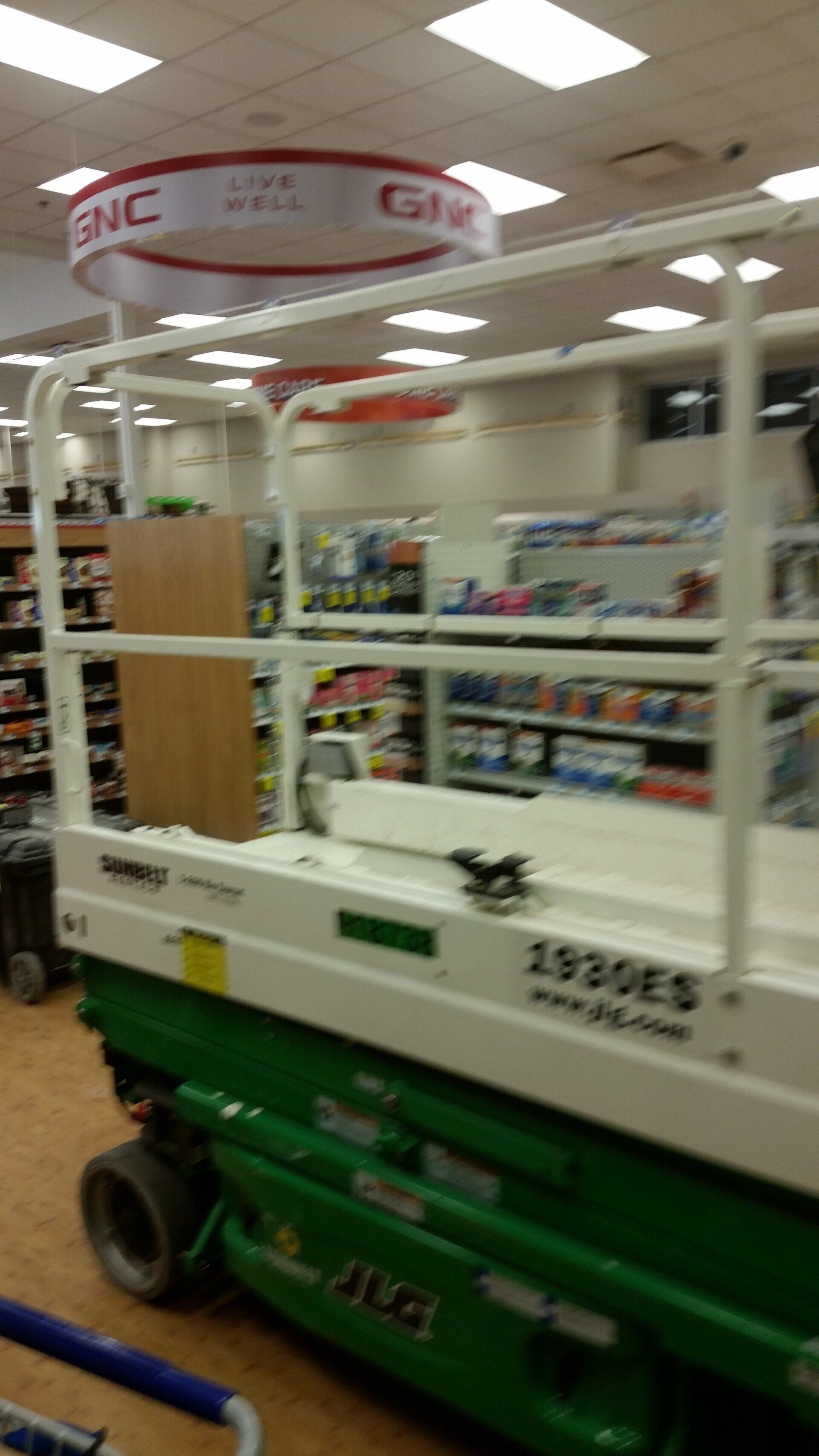 A green and white scissor lift is sitting in a store.