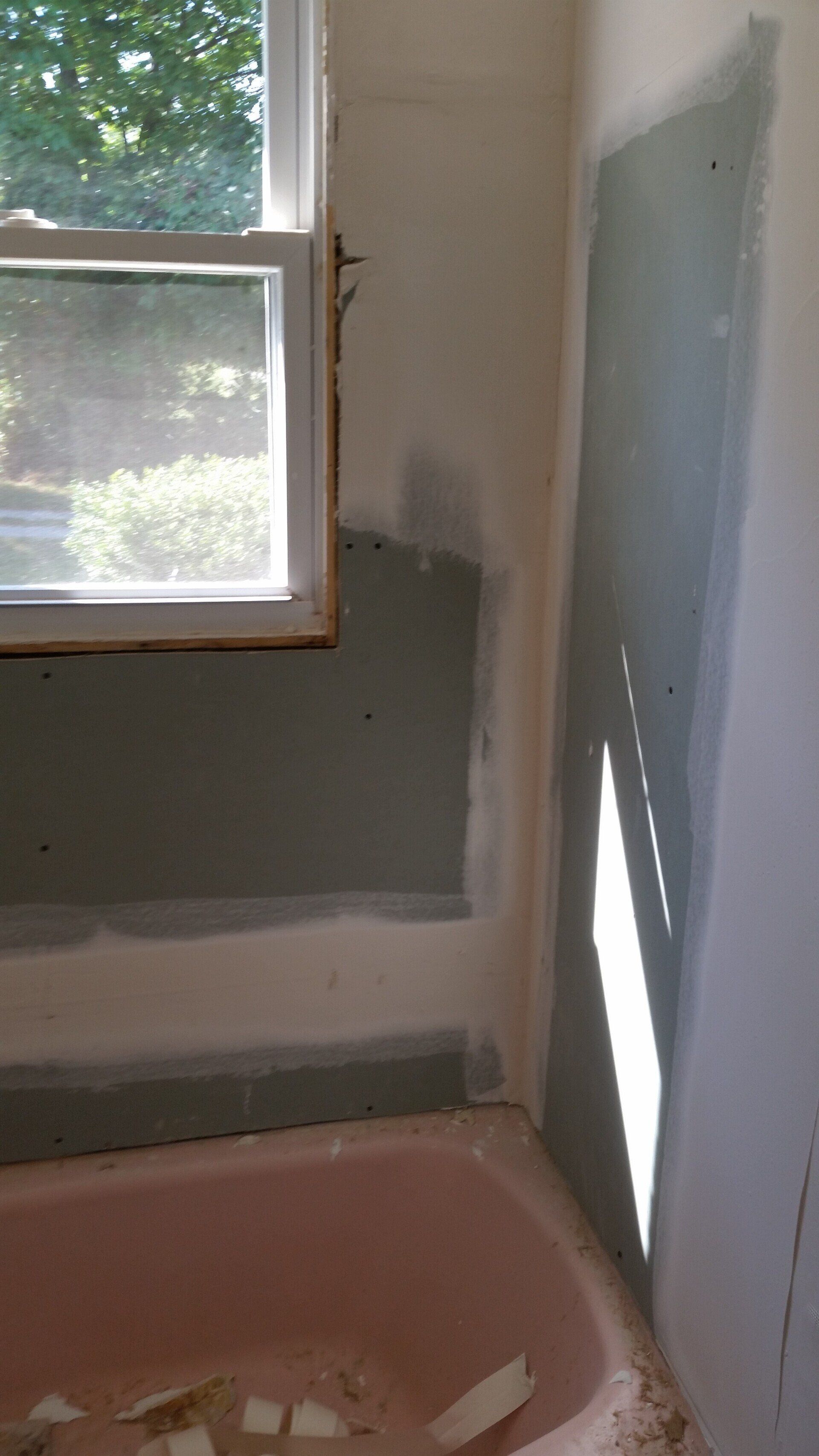 A pink bathtub is sitting in a bathroom next to a window.