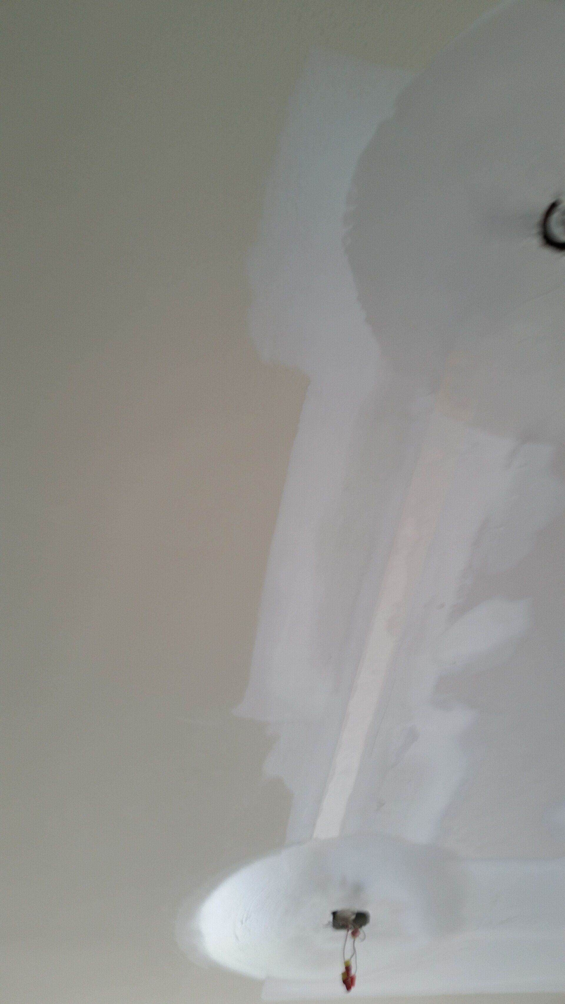 A close up of a white ceiling with a light hanging from it.