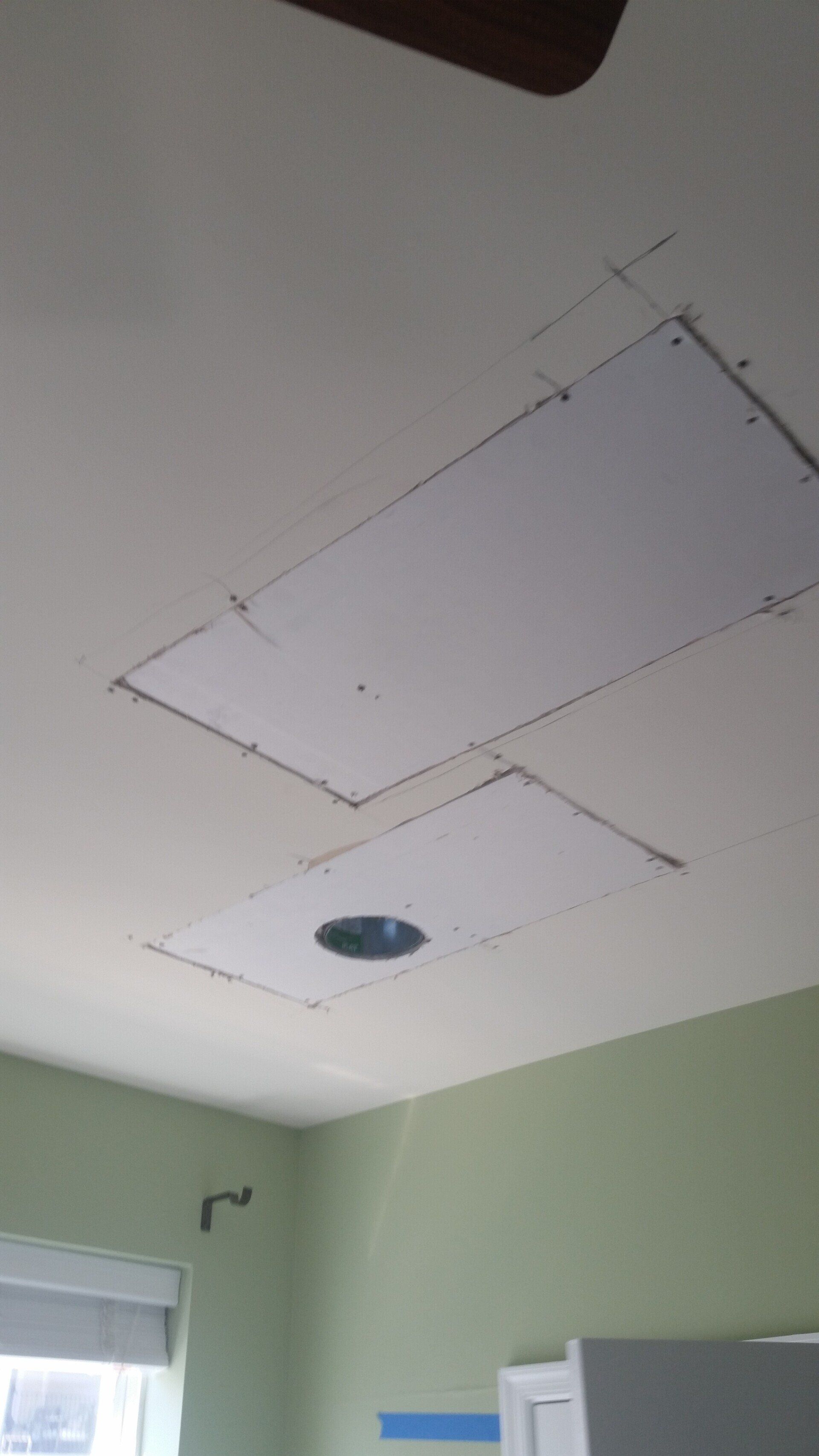 A room with a ceiling fan and a hole in the ceiling.