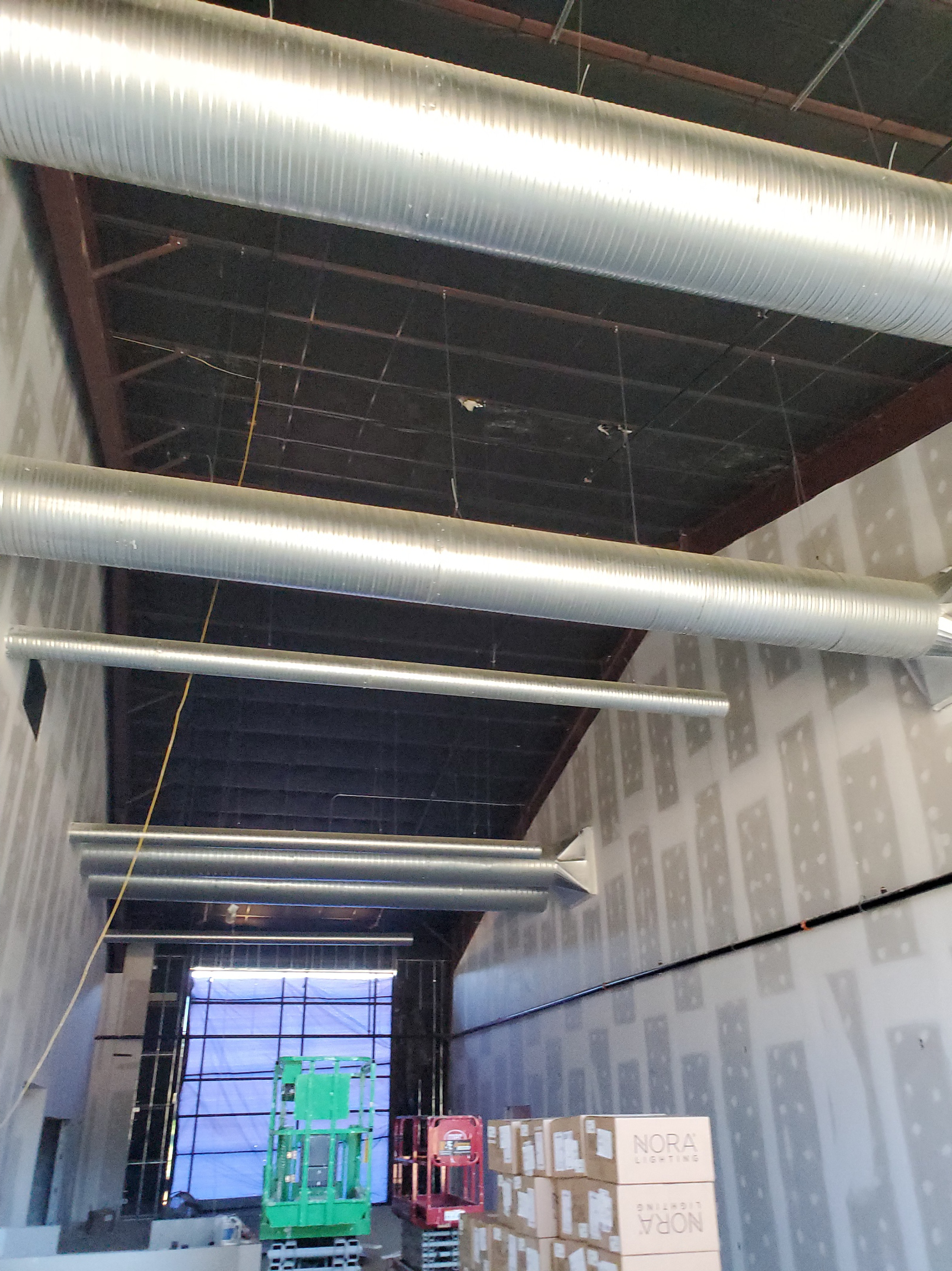 A warehouse with a lot of pipes hanging from the ceiling.