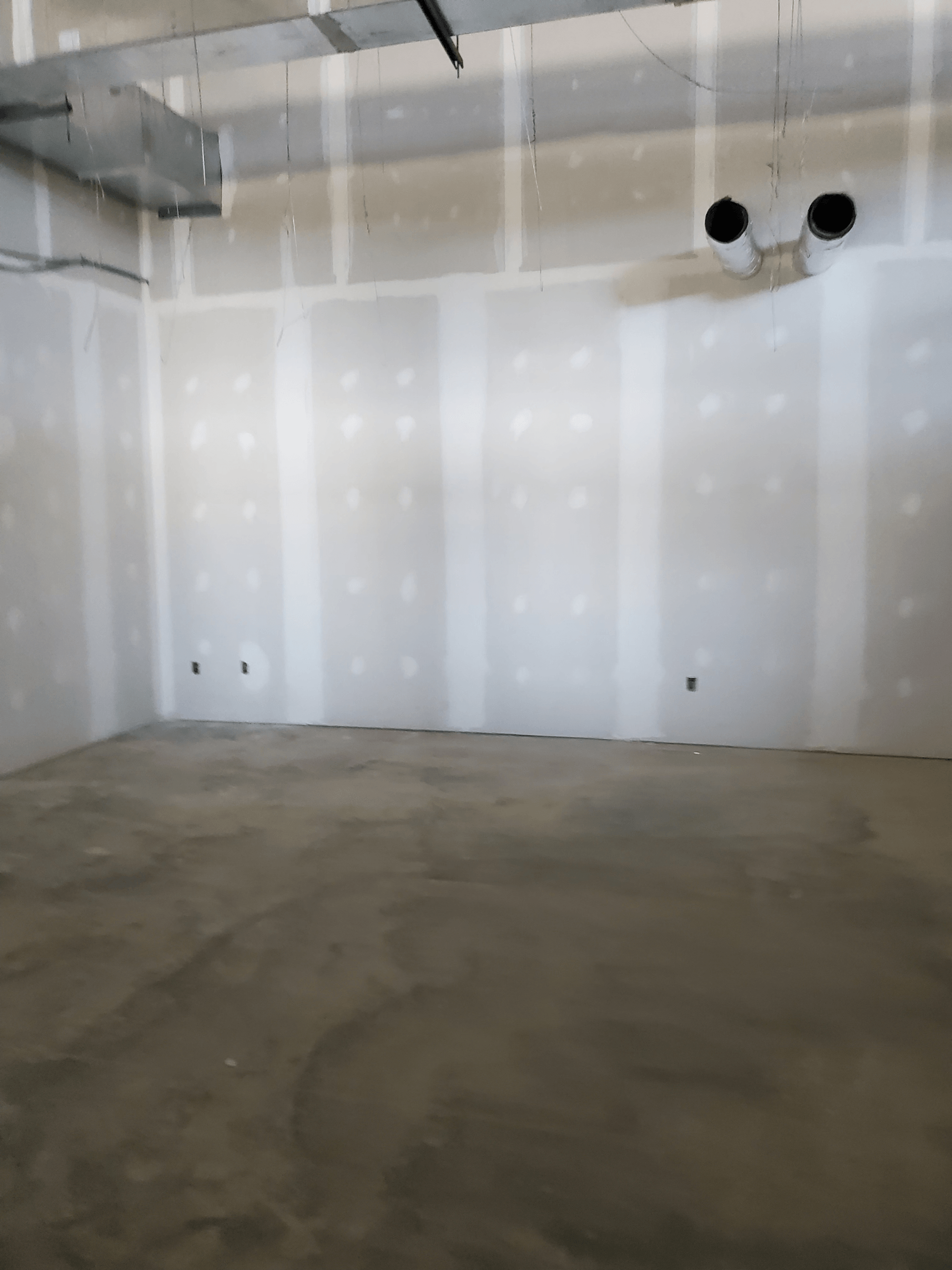 An empty room with white walls and a concrete floor