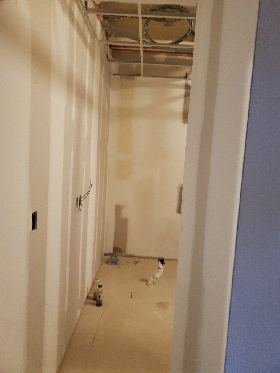 A long hallway with white walls and a ceiling fan.