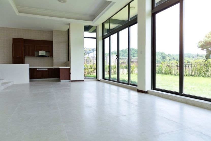 Modern open-plan living room with large glass doors, white tile floor, and a small kitchen area