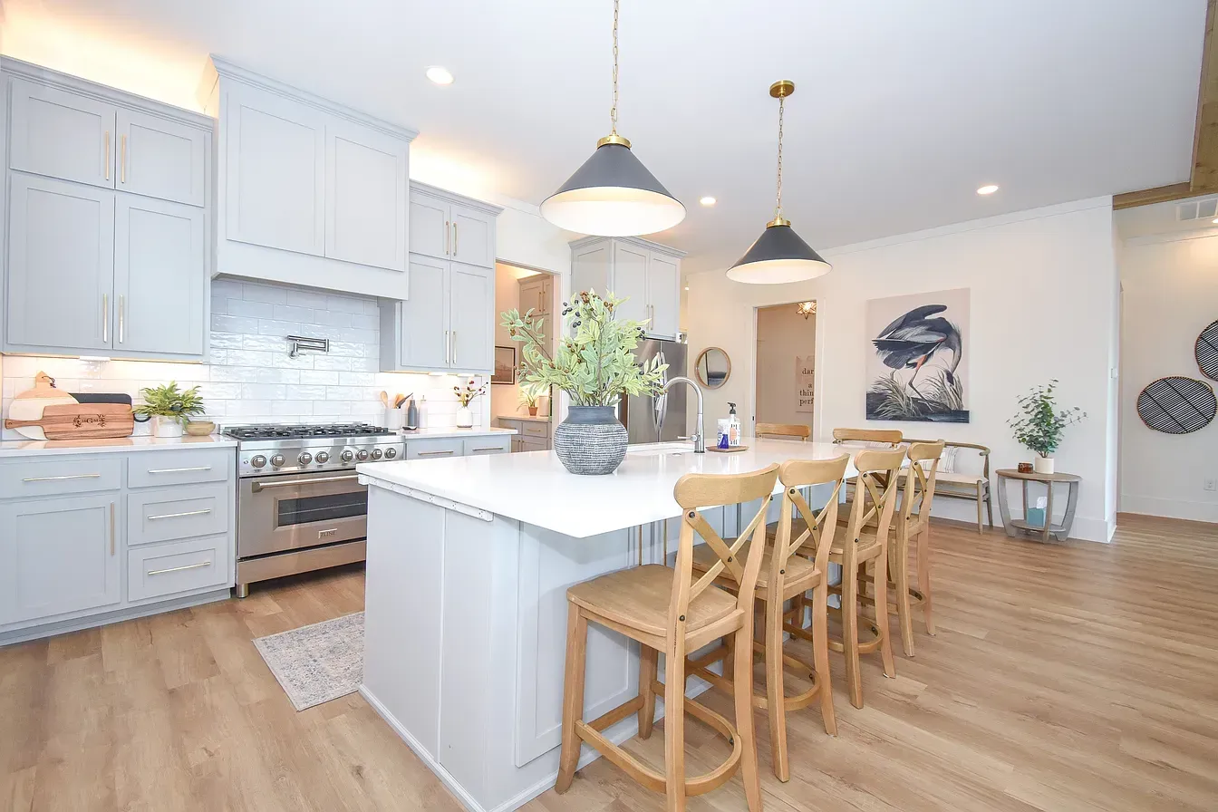 Bright modern kitchen with white cabinets, island, pendant lights, and wooden bar stools