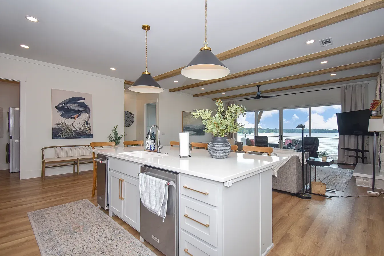 Modern open kitchen and dining area with island, pendant lights, and large windows overlooking water