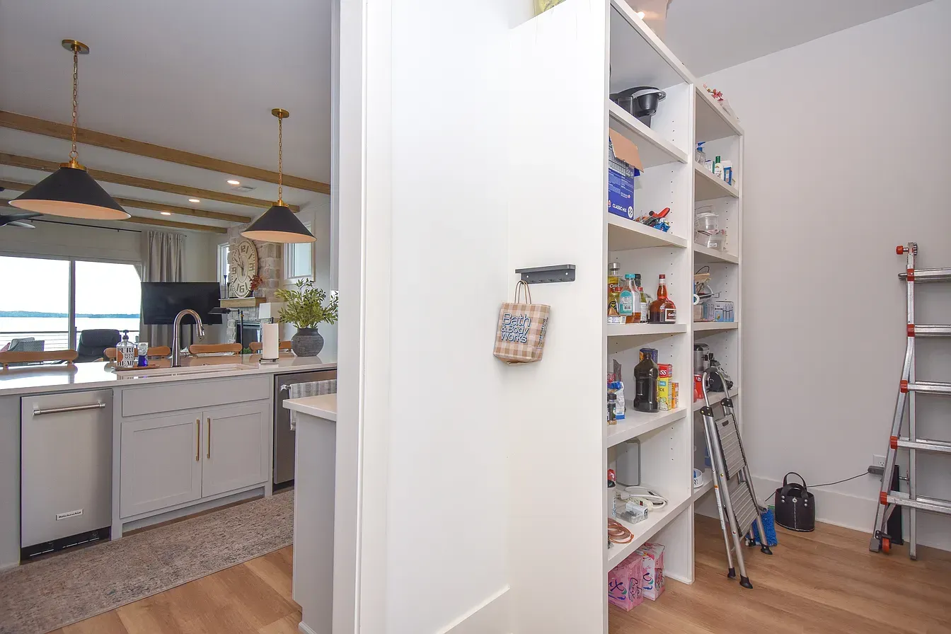 Open kitchen and play area with white shelving, wood floors, and a ladder by the wall