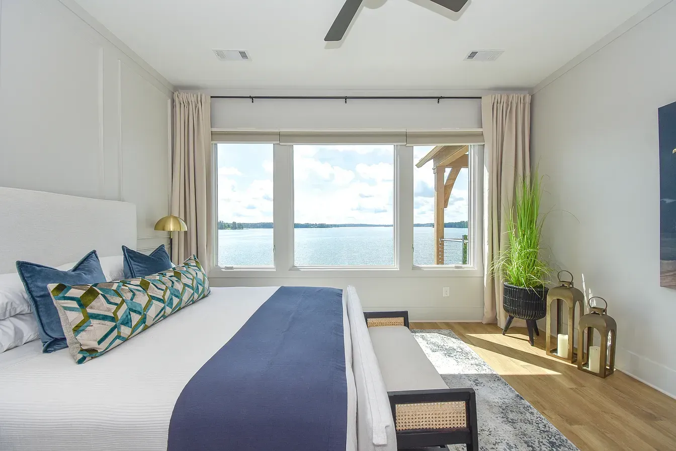 Bright bedroom with a large bed, blue accents, and ocean view through wide windows