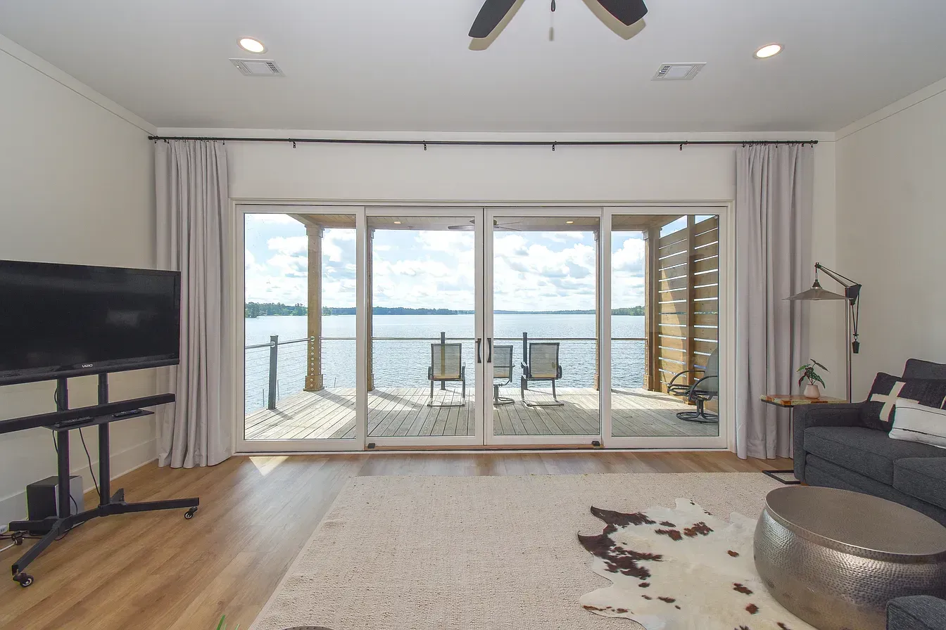 Bright living room with TV and sofa facing sliding doors to a balcony and ocean view