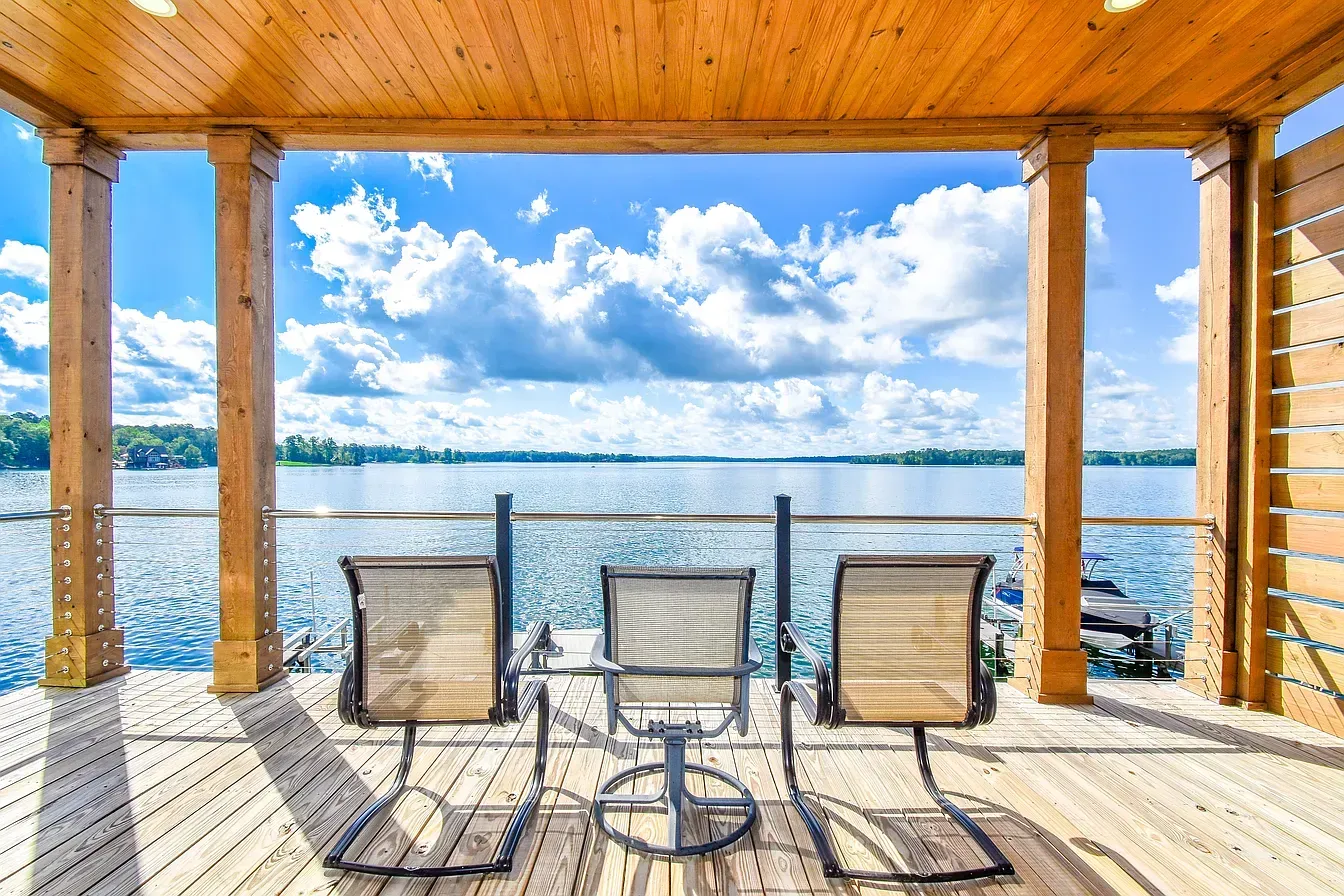 Covered lakeside patio with three chairs facing the water under a wooden roof