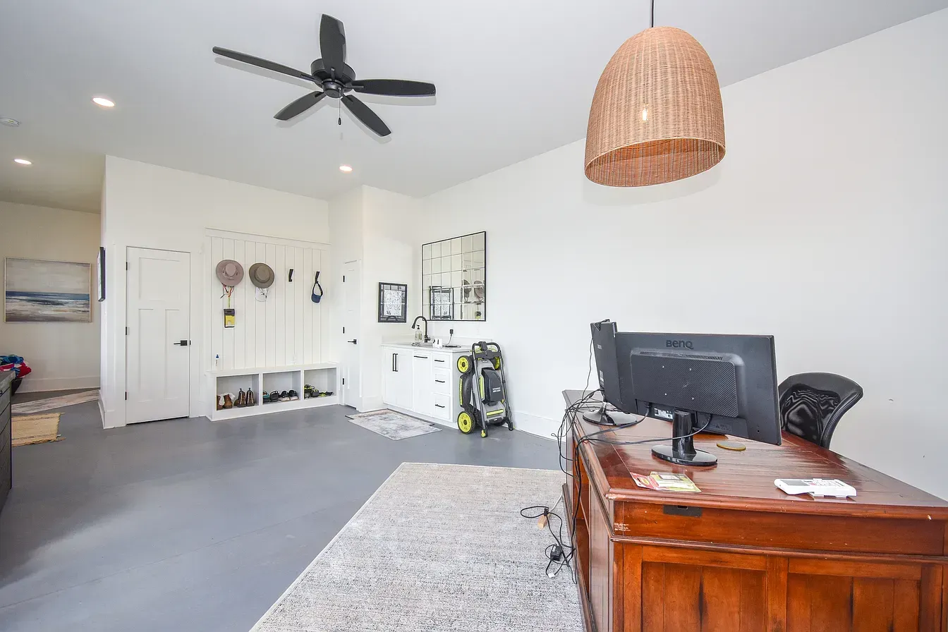 Bright bedroom with desk, monitor, ceiling fan, and white walls.