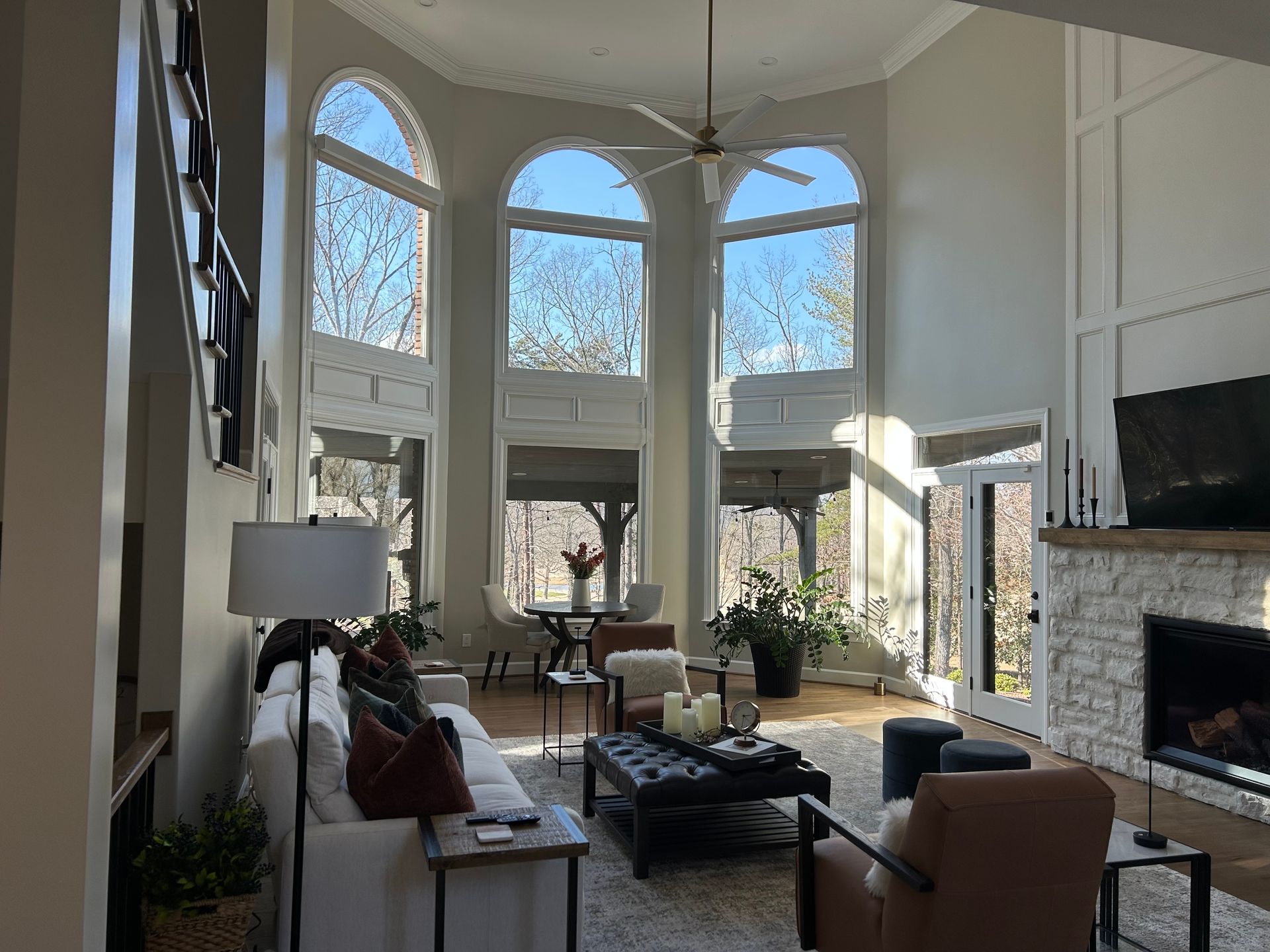 Bright living room with tall arched windows, fireplace, sofa, and glass coffee table in daylight