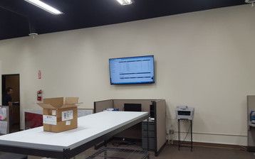 A box is sitting on a table in a room with a flat screen tv on the wall.