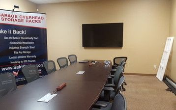 A conference room with a long table and chairs and a flat screen tv.