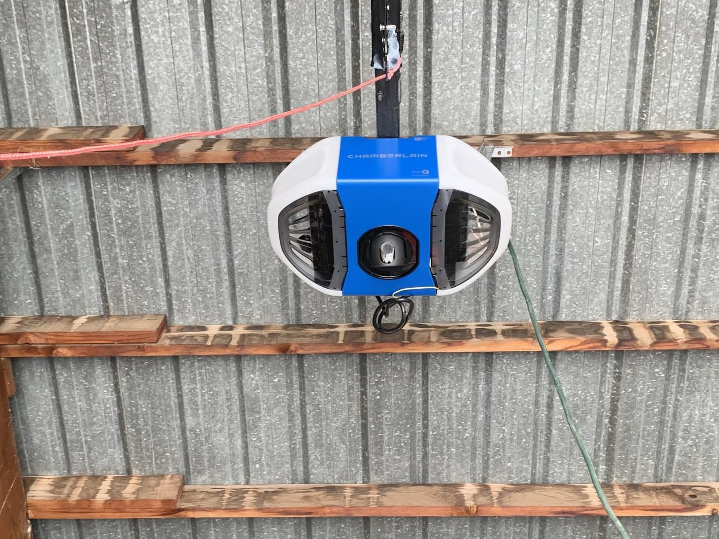 A blue and white garage door opener is hanging from the ceiling of a building.