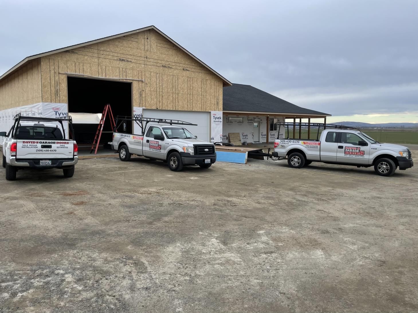 Three trucks are parked in front of a building under construction.