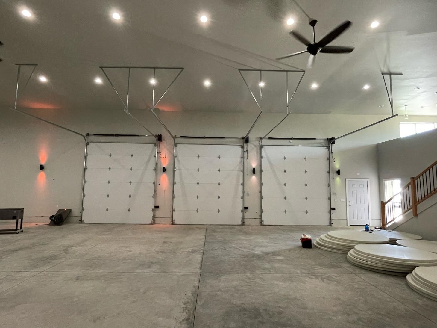 A large empty garage with three garage doors and a ceiling fan