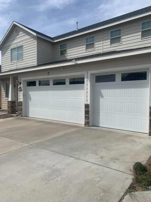 A large house with two white garage doors and a driveway.