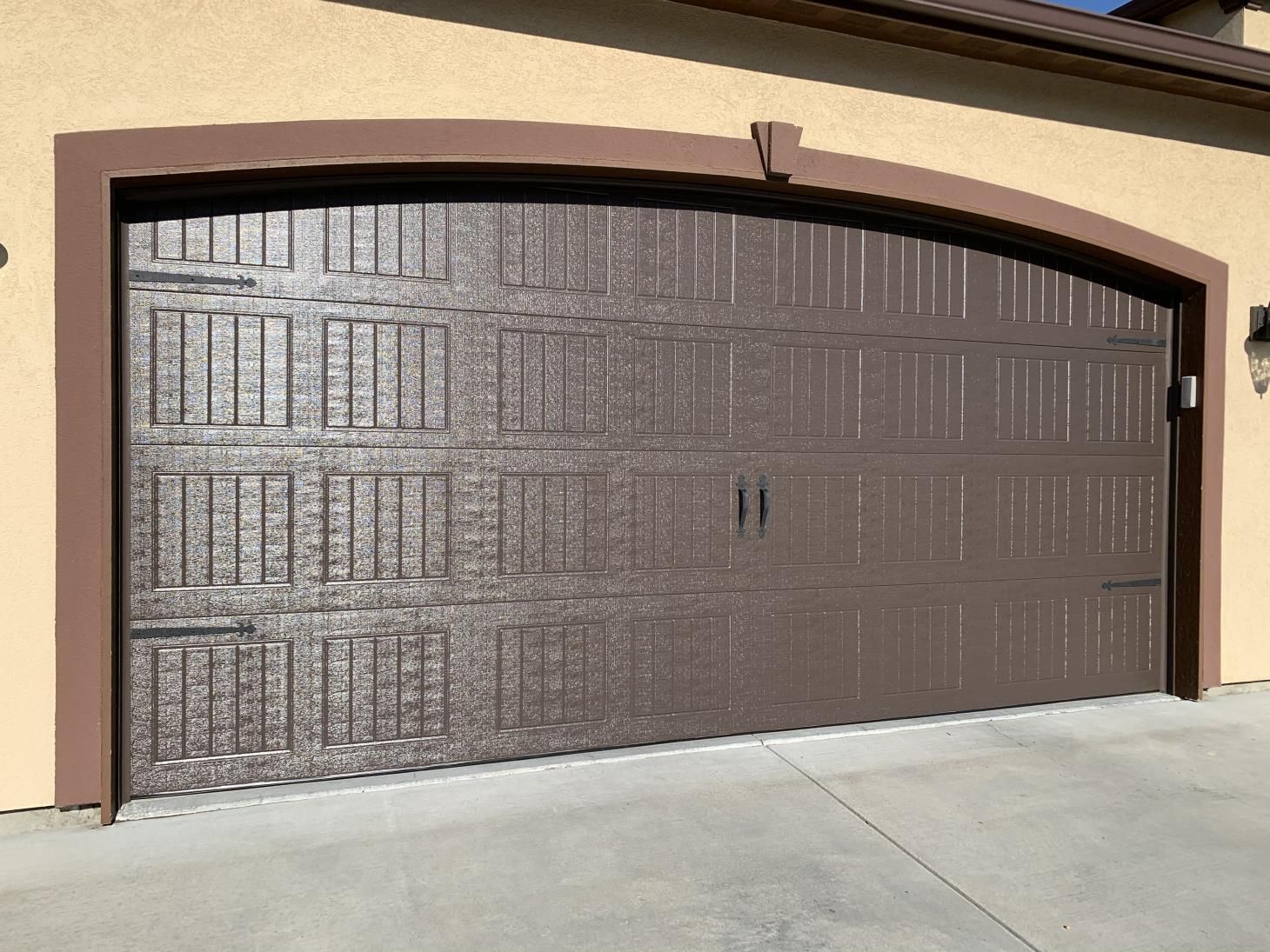 A large brown garage door is on the side of a house.