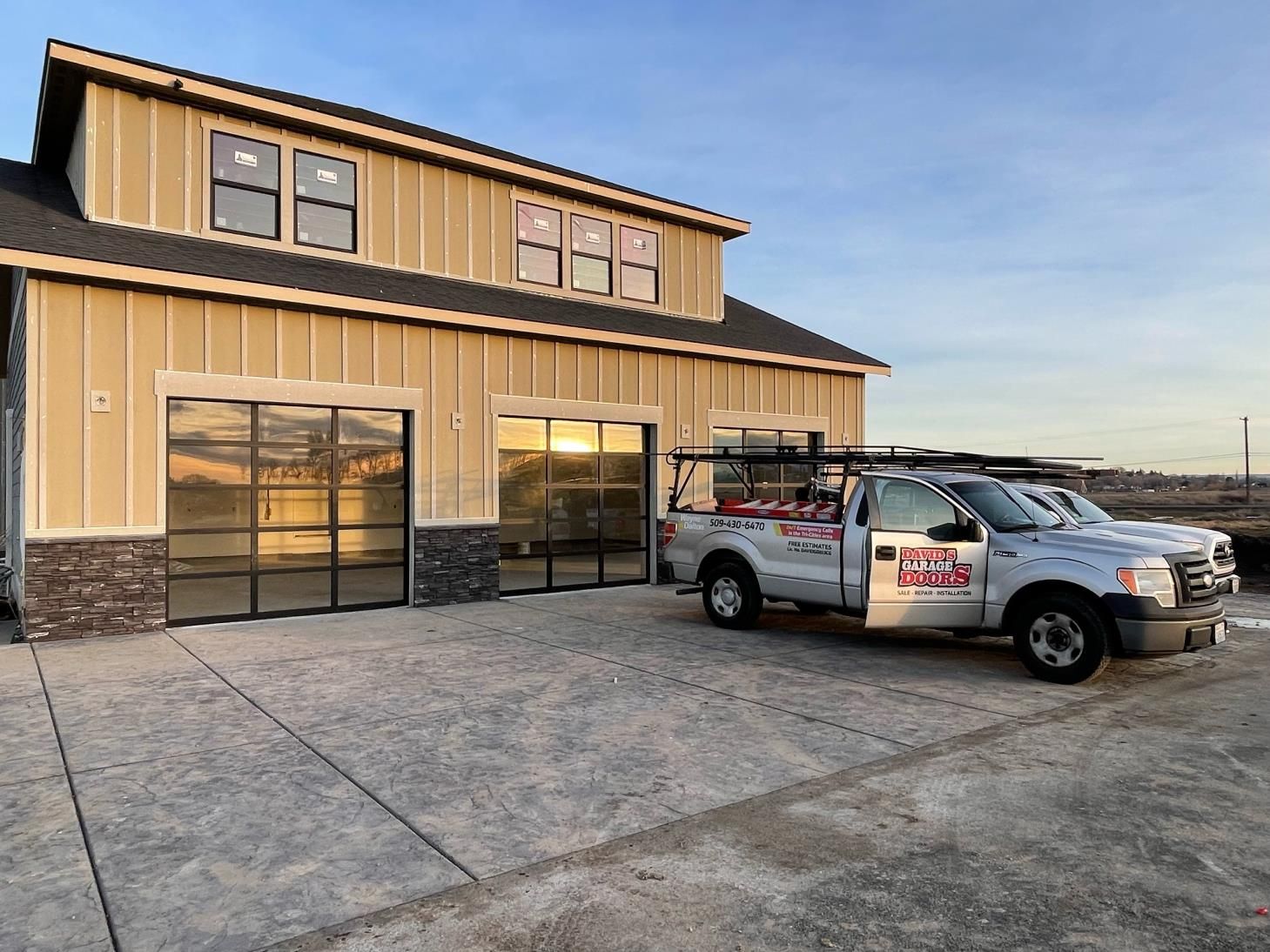 Two white trucks are parked in front of a building.