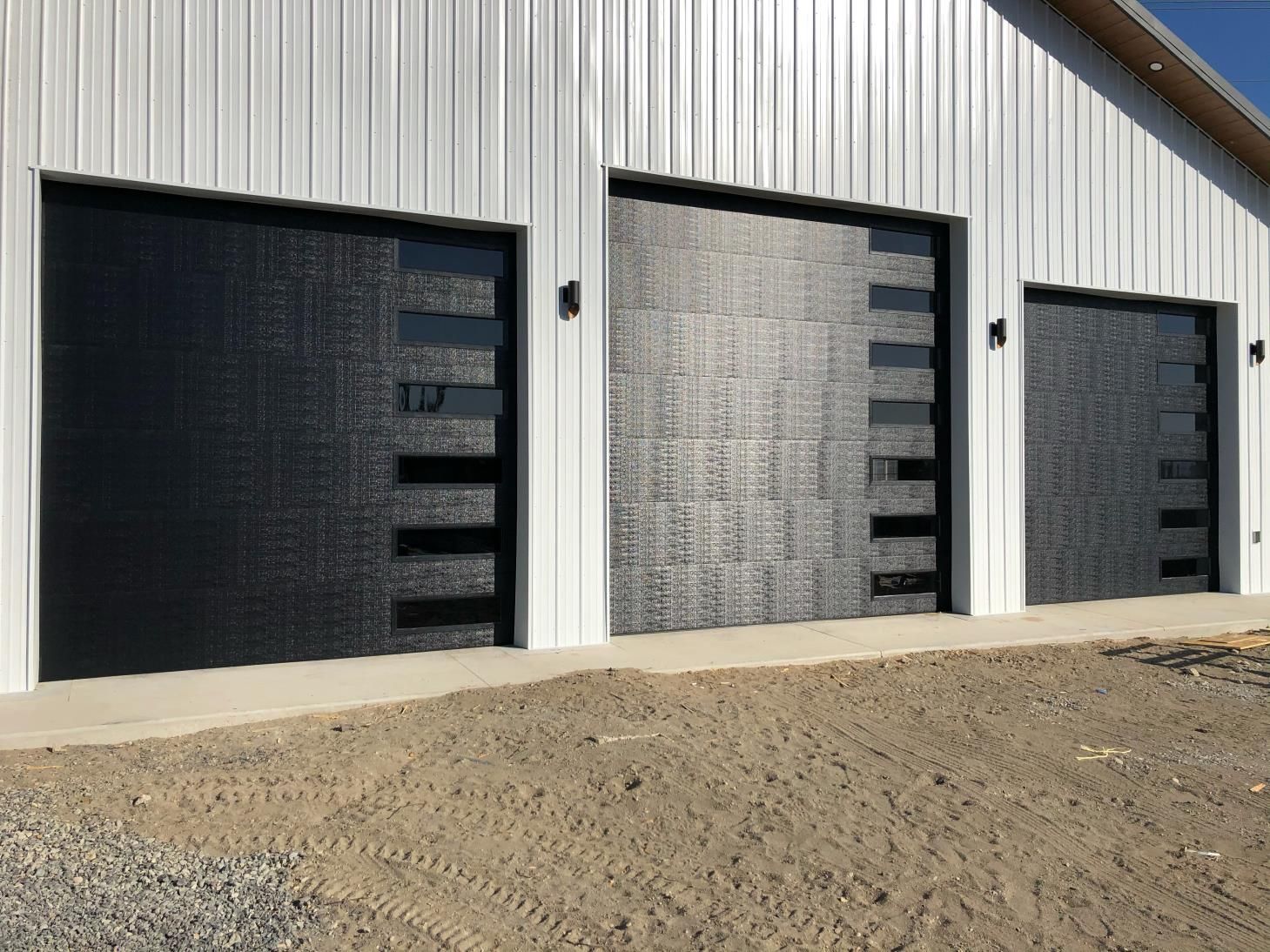 Three garage doors are lined up in front of a white building.