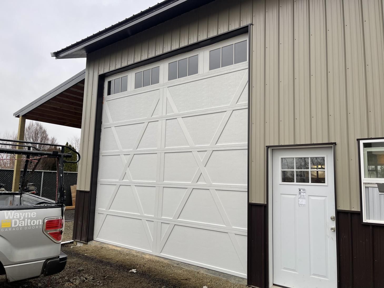 A white truck is parked in front of a garage door.