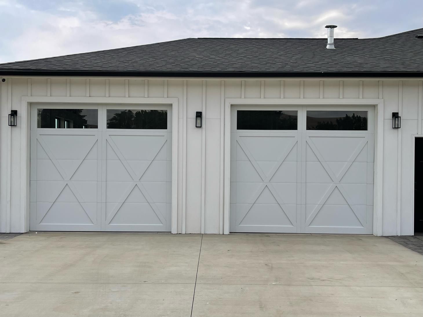 A white garage with two white garage doors and a gray roof.