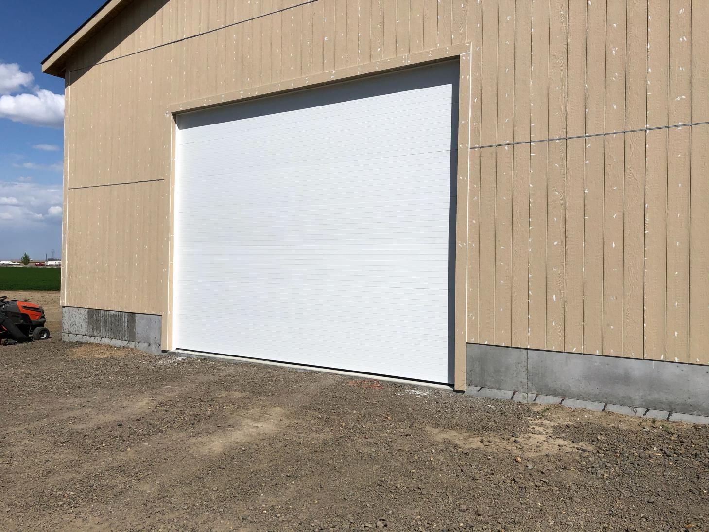 A white garage door is sitting on the side of a building.