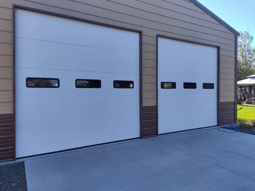 A garage with two white garage doors and brown siding