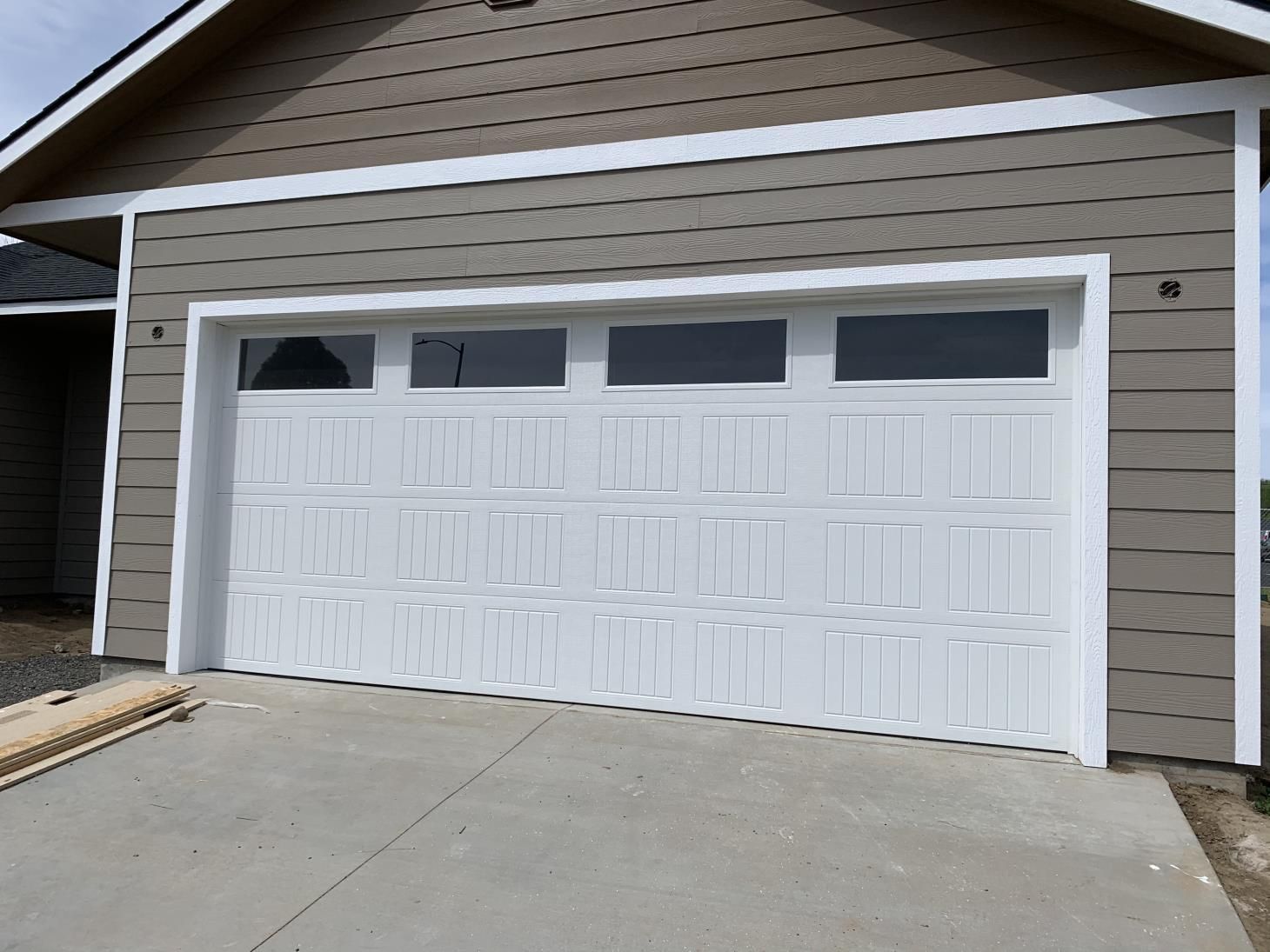 A garage with a white door and brown siding