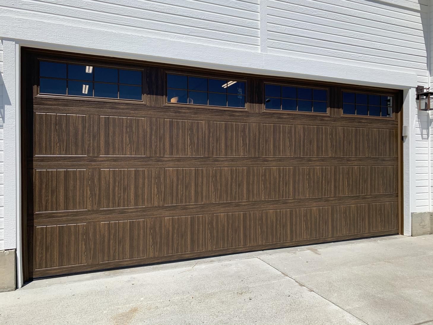 A large brown garage door is on a white brick building.