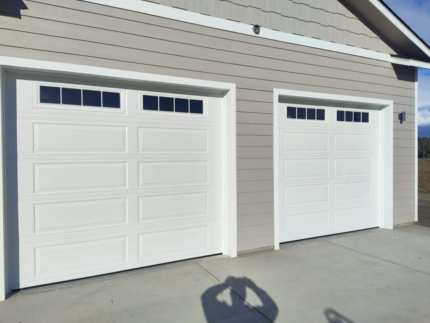 Two white garage doors on the side of a house