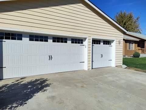 A house with three white garage doors and a driveway.