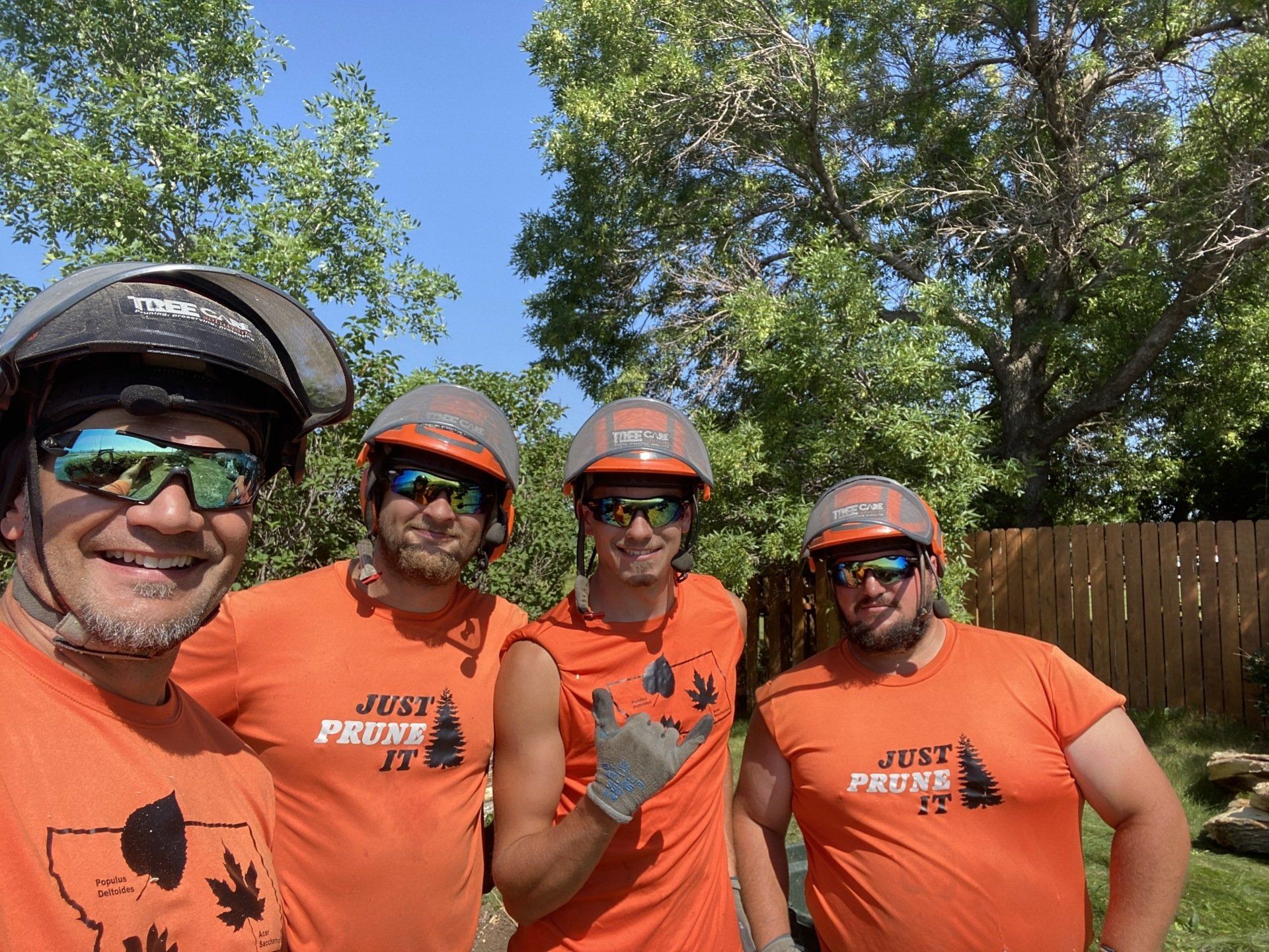 A group of men wearing orange shirts and helmets are posing for a picture.