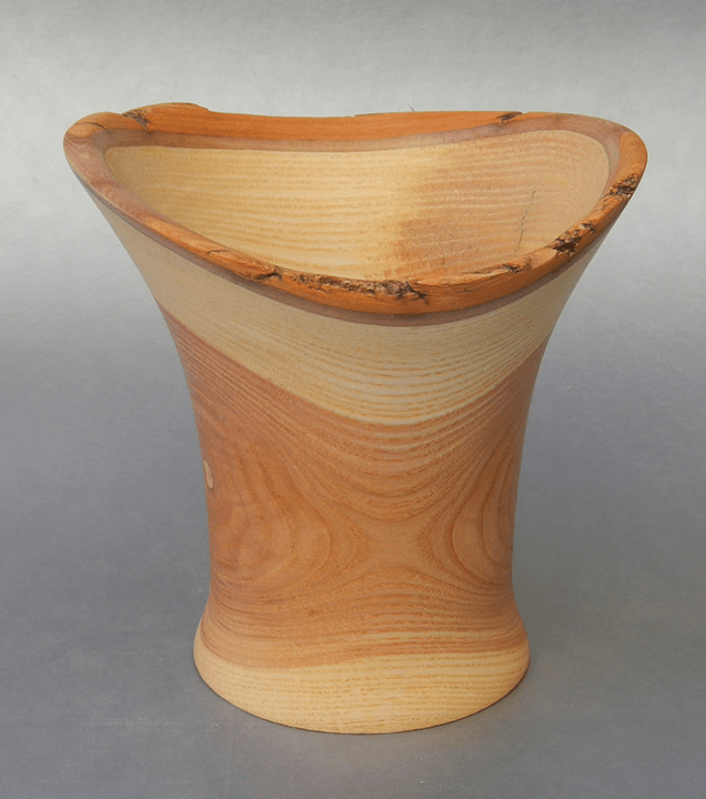 A wooden vase is sitting on a gray surface