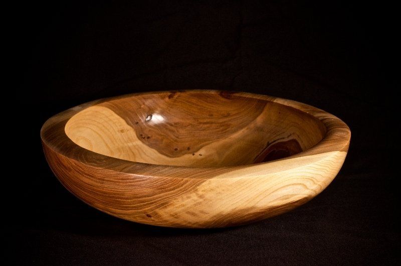 A wooden bowl is sitting on a black surface.