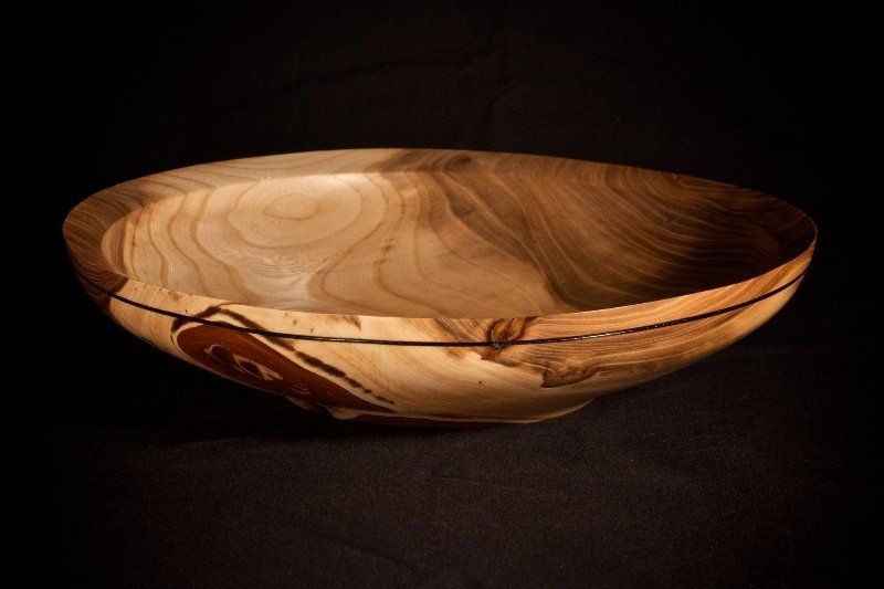 A wooden bowl is sitting on a black surface.