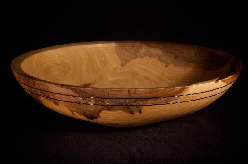 A wooden bowl is sitting on a black table.