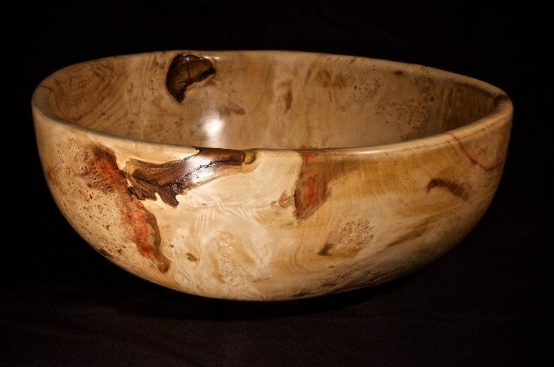A wooden bowl is sitting on a black surface.